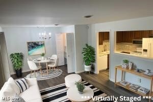 living room featuring an inviting chandelier and dark wood-type flooring