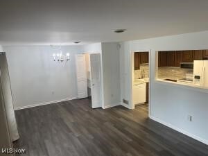 unfurnished living room with a notable chandelier and dark hardwood / wood-style flooring