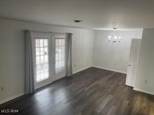 spare room featuring french doors, a chandelier, and dark wood-type flooring