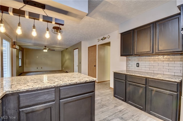 kitchen with a textured ceiling, light hardwood / wood-style floors, ceiling fan, and pendant lighting