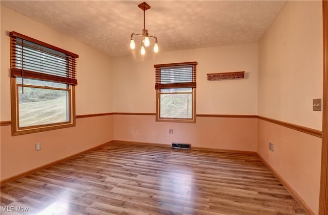 spare room with a chandelier, a textured ceiling, and hardwood / wood-style flooring