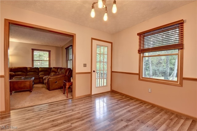 living room with a textured ceiling, light hardwood / wood-style floors, and a wealth of natural light