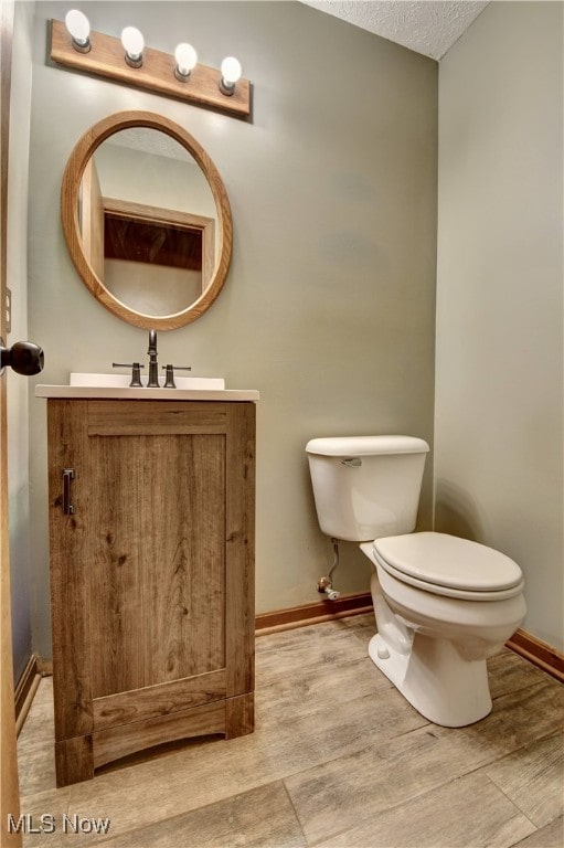 bathroom with a textured ceiling, vanity, toilet, and hardwood / wood-style flooring