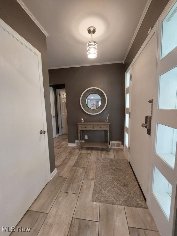 corridor with light hardwood / wood-style flooring and crown molding