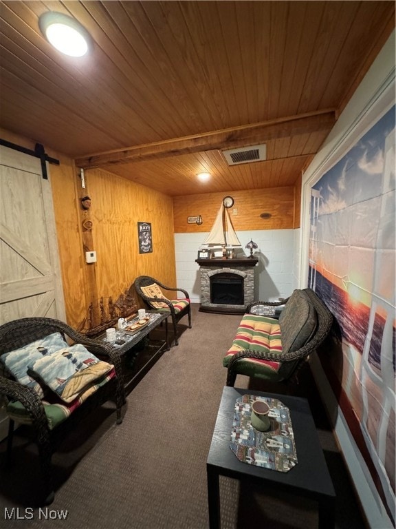 sitting room featuring carpet floors, wood ceiling, wood walls, and a barn door