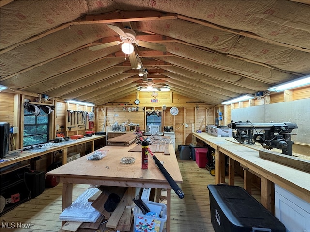 interior space featuring a workshop area, lofted ceiling, wood walls, and light wood-type flooring