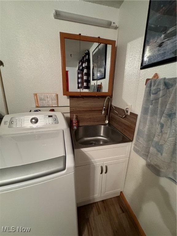 clothes washing area featuring dark wood-type flooring, washer / dryer, sink, and cabinets