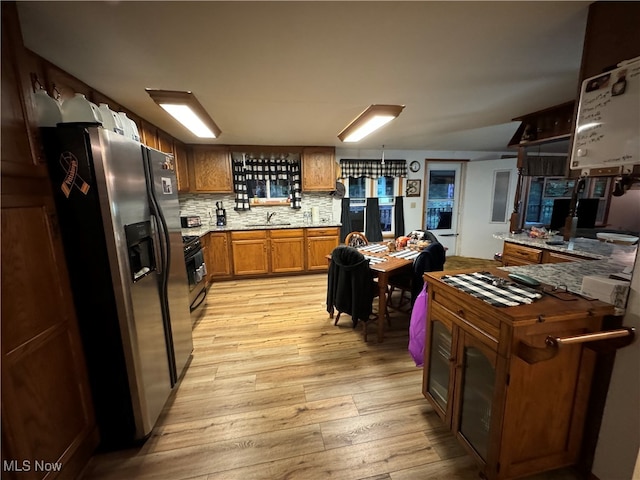 kitchen featuring tasteful backsplash, light wood-type flooring, gas stove, sink, and stainless steel fridge with ice dispenser