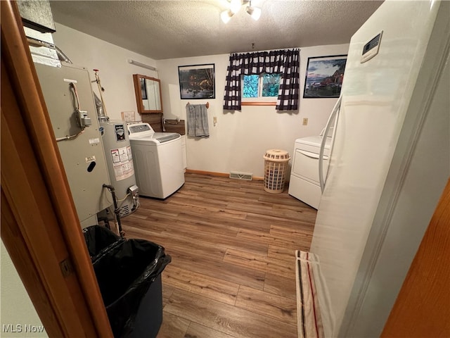 laundry room with a textured ceiling, light hardwood / wood-style floors, and water heater