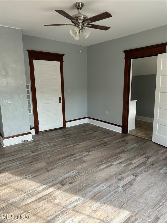 spare room featuring wood finished floors, baseboards, and a ceiling fan