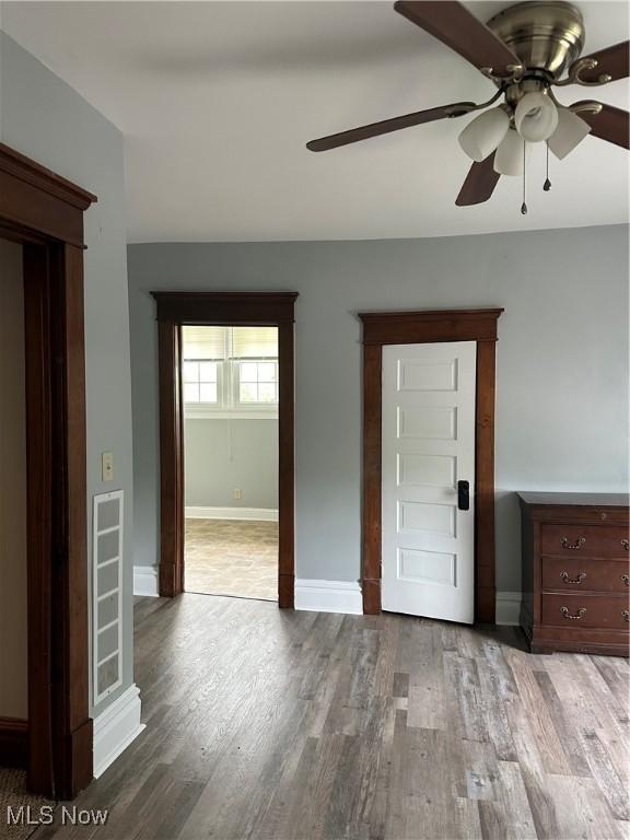 unfurnished room featuring baseboards, a ceiling fan, and wood finished floors