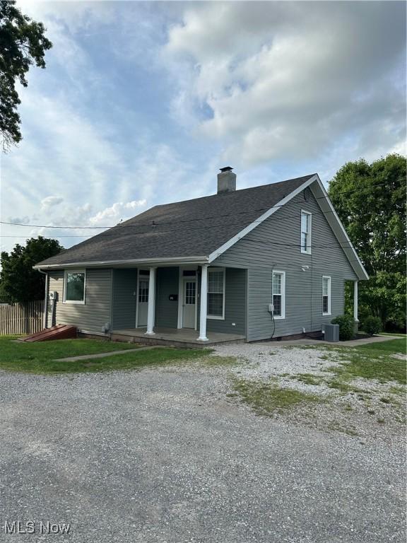view of front facade featuring fence, driveway, a chimney, and covered porch