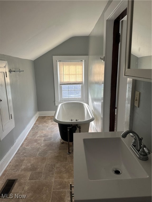 bathroom featuring lofted ceiling, a bathtub, and sink