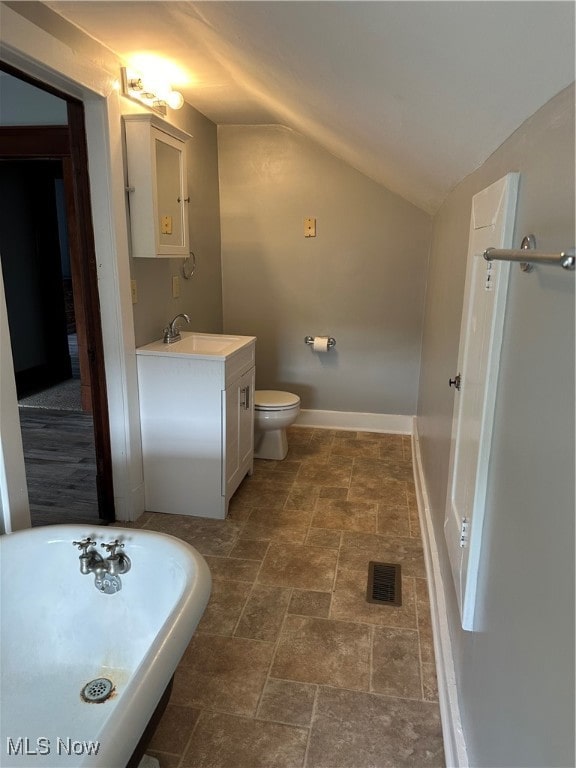 bathroom with lofted ceiling, vanity, and toilet