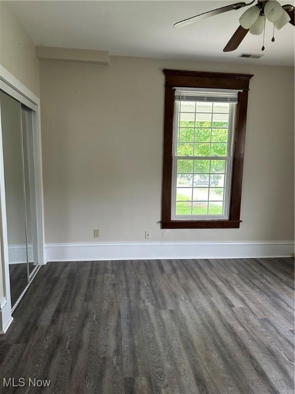 unfurnished room featuring visible vents, baseboards, a ceiling fan, and dark wood finished floors