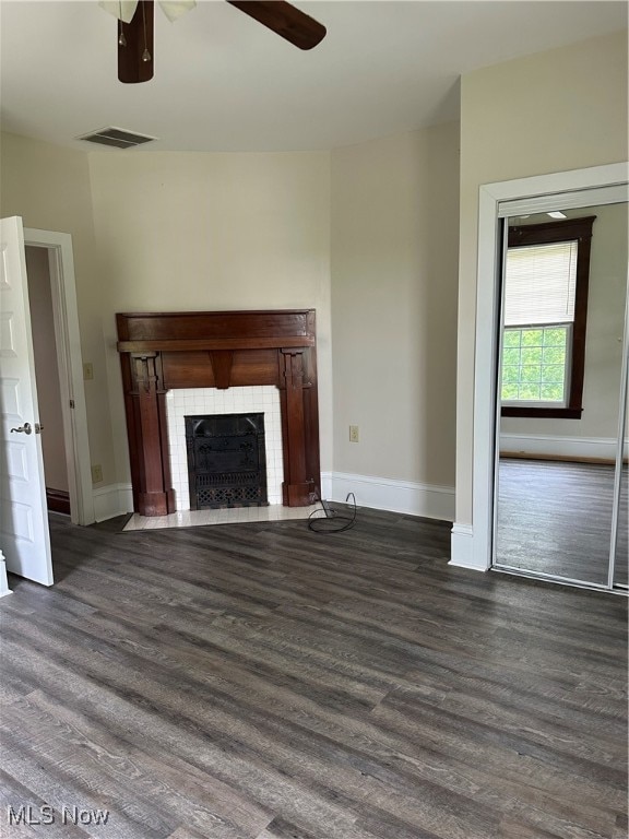 unfurnished living room featuring ceiling fan, a fireplace, and dark hardwood / wood-style flooring