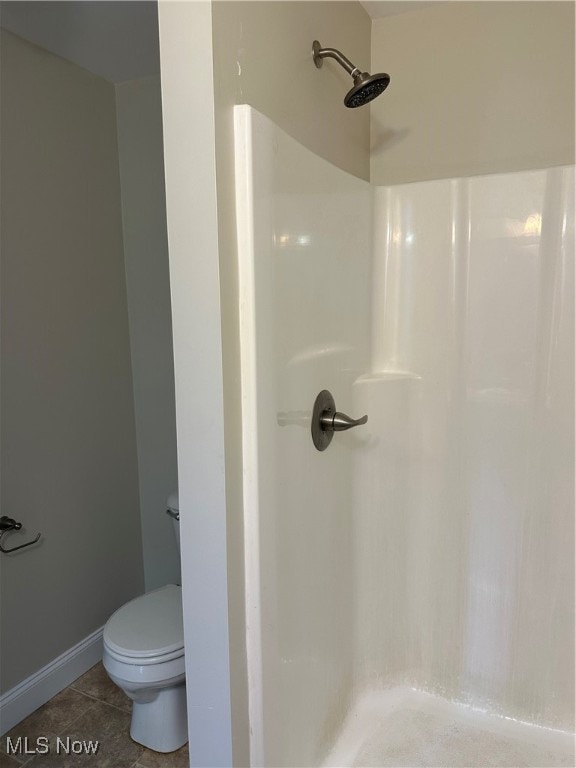 bathroom with tile patterned flooring, walk in shower, and toilet