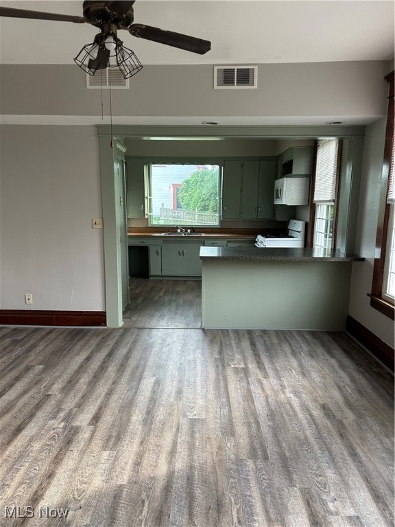 kitchen featuring green cabinetry, white appliances, kitchen peninsula, and dark wood-type flooring