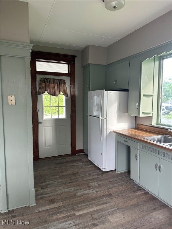 kitchen featuring white refrigerator, sink, dark hardwood / wood-style flooring, and butcher block counters