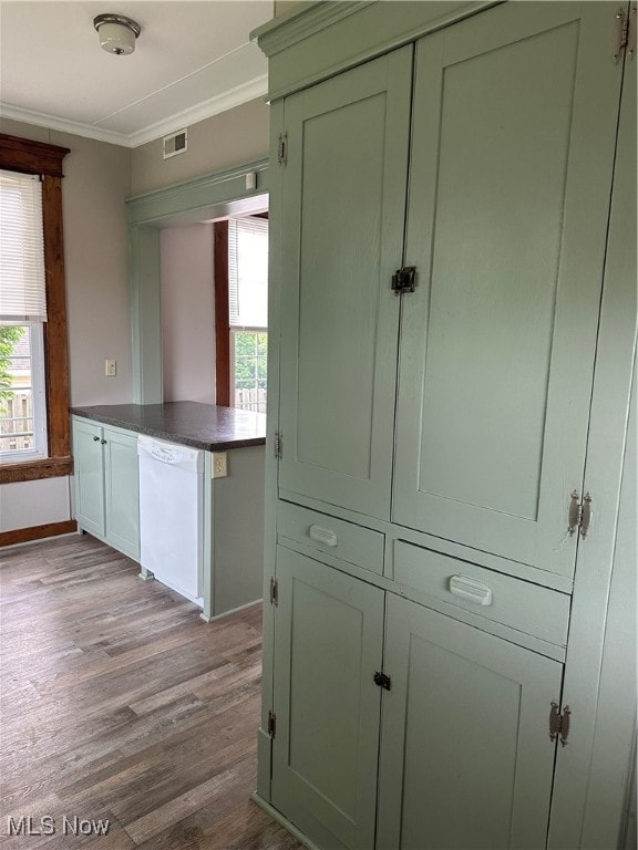 kitchen featuring green cabinetry, dishwasher, light wood-type flooring, and ornamental molding