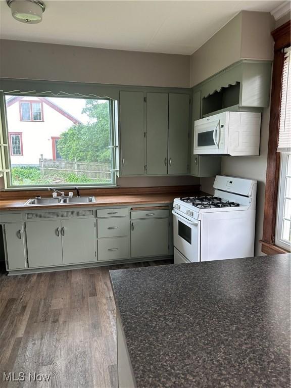 kitchen featuring wood finished floors, a sink, white appliances, and plenty of natural light
