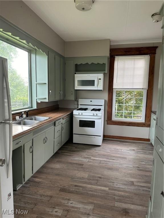 kitchen featuring a sink, baseboards, white appliances, and dark wood-style floors