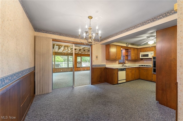 kitchen featuring white appliances, sink, dark carpet, and decorative light fixtures