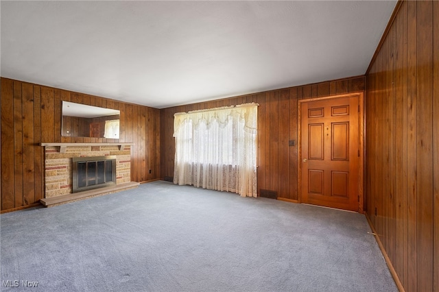 unfurnished living room with light carpet, wooden walls, and a fireplace