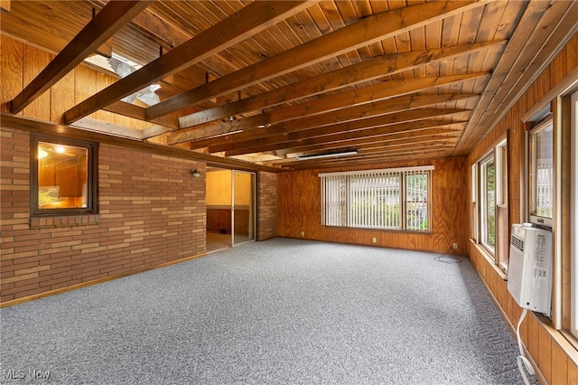 interior space with wood ceiling, brick wall, carpet flooring, a skylight, and wooden walls