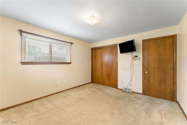 unfurnished bedroom with light carpet and a closet