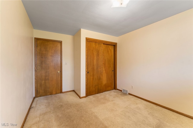 unfurnished bedroom with a closet and light colored carpet