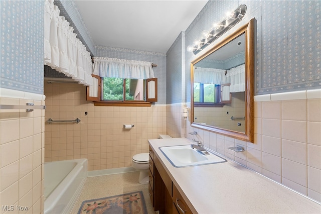 bathroom with tile walls, a tub, vanity, and toilet