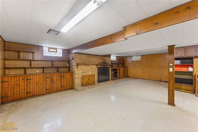 basement featuring a brick fireplace and wooden walls