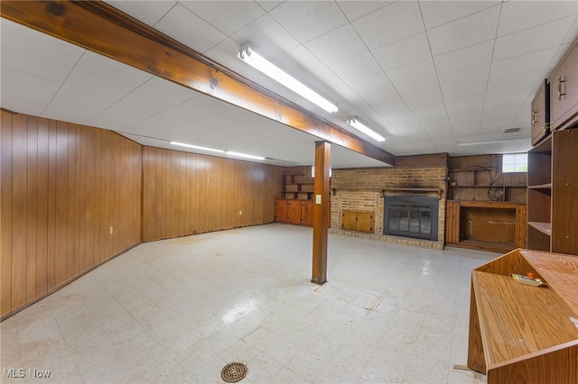 basement with wooden walls and a brick fireplace