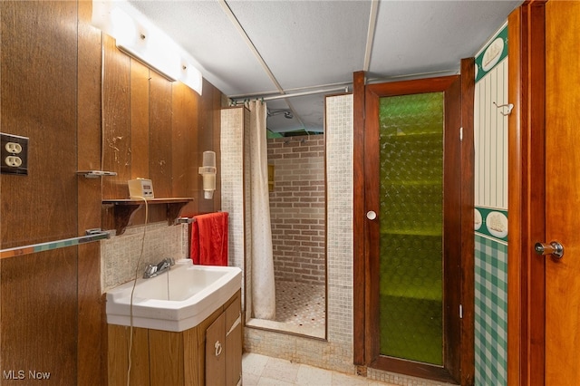 bathroom featuring walk in shower, vanity, and brick wall