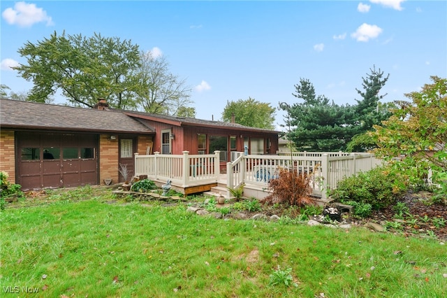 exterior space featuring a garage, a wooden deck, and a yard