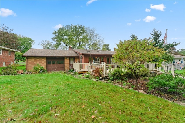 back of house featuring a garage, a deck, and a lawn