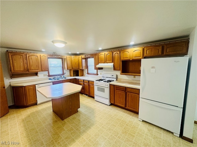 kitchen featuring white appliances, a center island, and sink