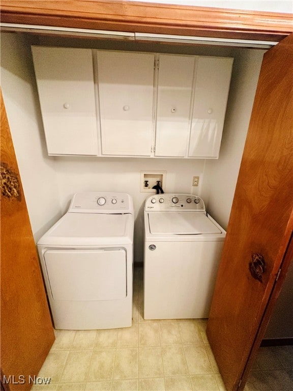 laundry room featuring light tile patterned flooring, washer and dryer, and cabinets