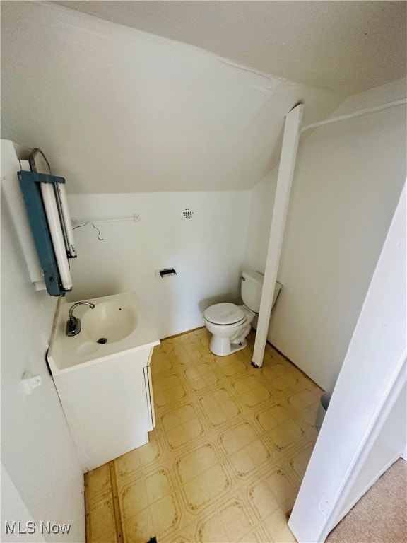 bathroom featuring lofted ceiling, vanity, and toilet