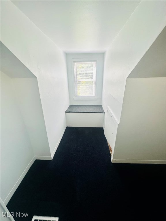 hall featuring dark colored carpet