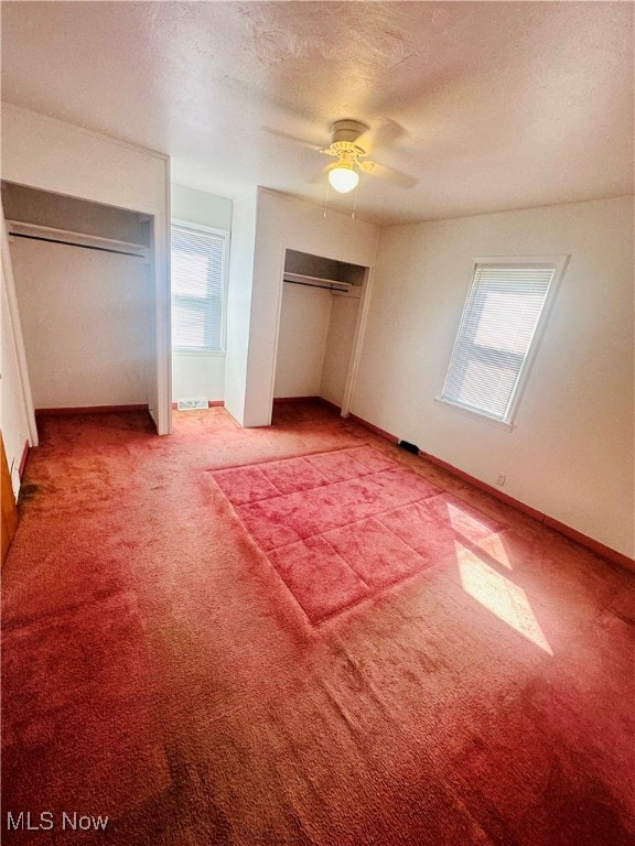 unfurnished bedroom featuring ceiling fan, a textured ceiling, carpet, and multiple windows