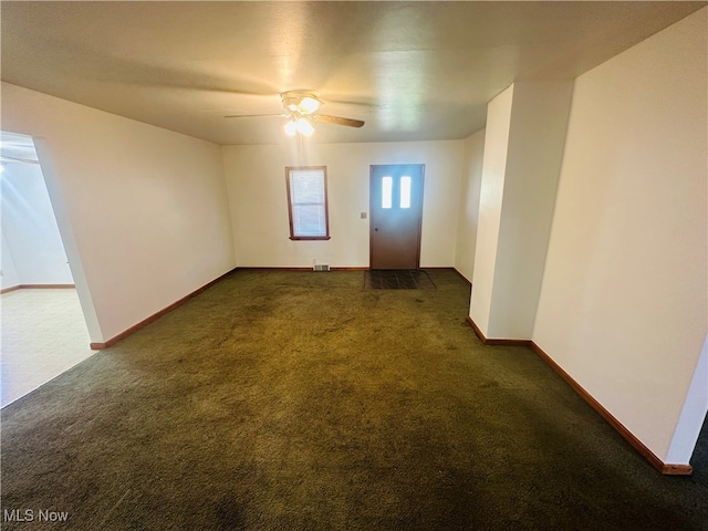 spare room with dark carpet and ceiling fan