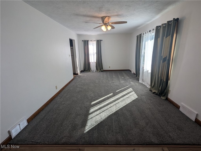 carpeted spare room featuring a textured ceiling, ceiling fan, and a wealth of natural light