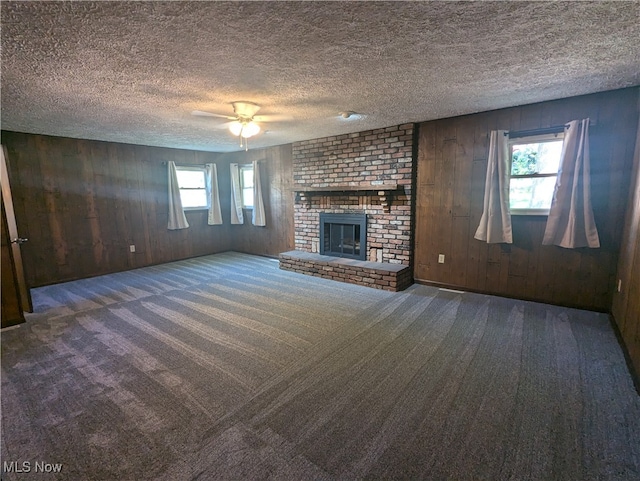 unfurnished living room featuring a textured ceiling, a healthy amount of sunlight, carpet, and a brick fireplace