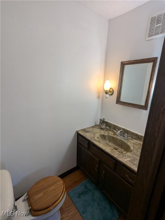 bathroom featuring wood-type flooring, vanity, and toilet