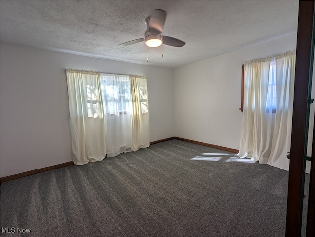 spare room with a textured ceiling, dark carpet, and ceiling fan