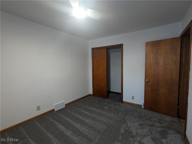 unfurnished bedroom with a closet, dark colored carpet, and ceiling fan