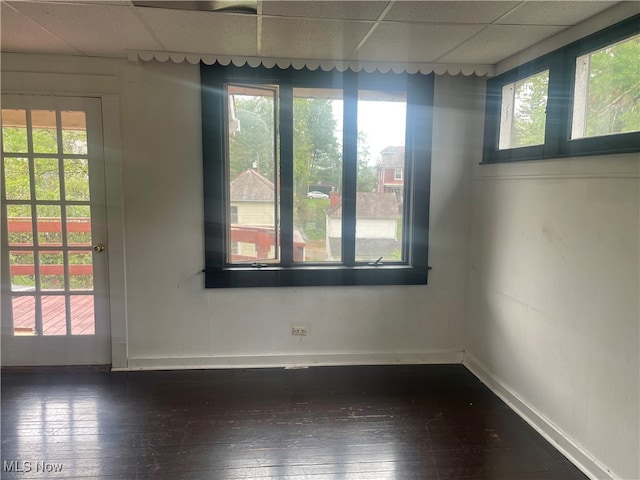 unfurnished room featuring a drop ceiling, dark wood-type flooring, and a healthy amount of sunlight