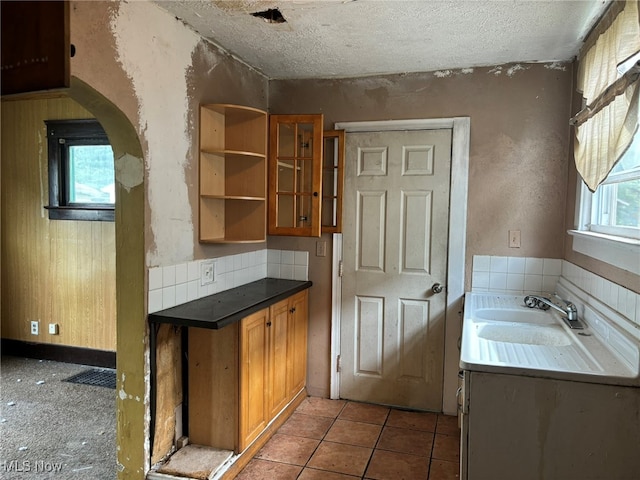 bar with a textured ceiling, sink, and tile patterned floors